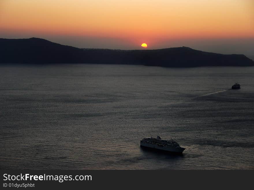 A beautiful sun setting behind the mountain over Santorini island. A beautiful sun setting behind the mountain over Santorini island