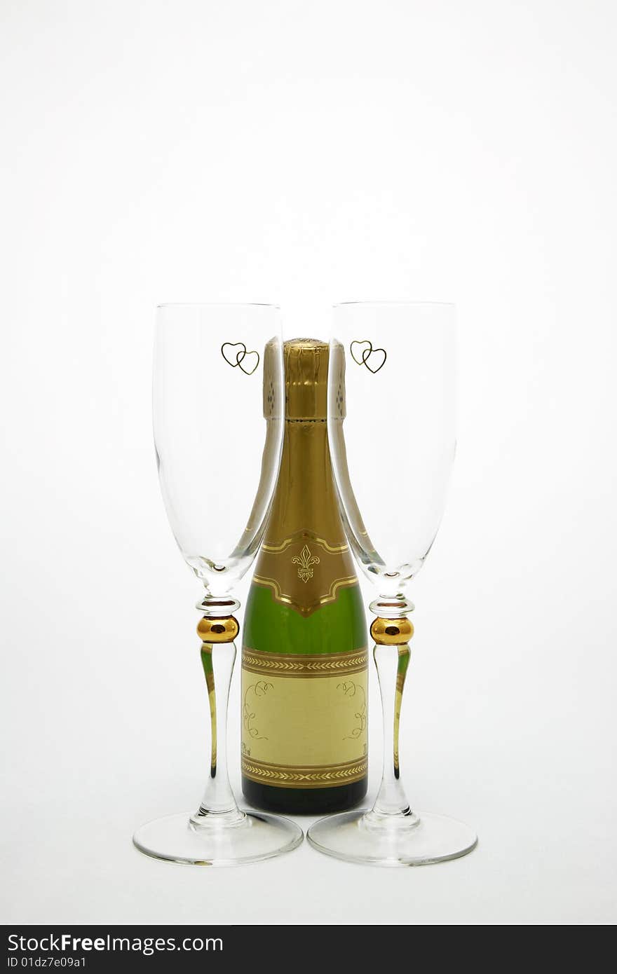 A Champagne bottle centered by two Champagne glasses with gold hearts at the top. A Champagne bottle centered by two Champagne glasses with gold hearts at the top