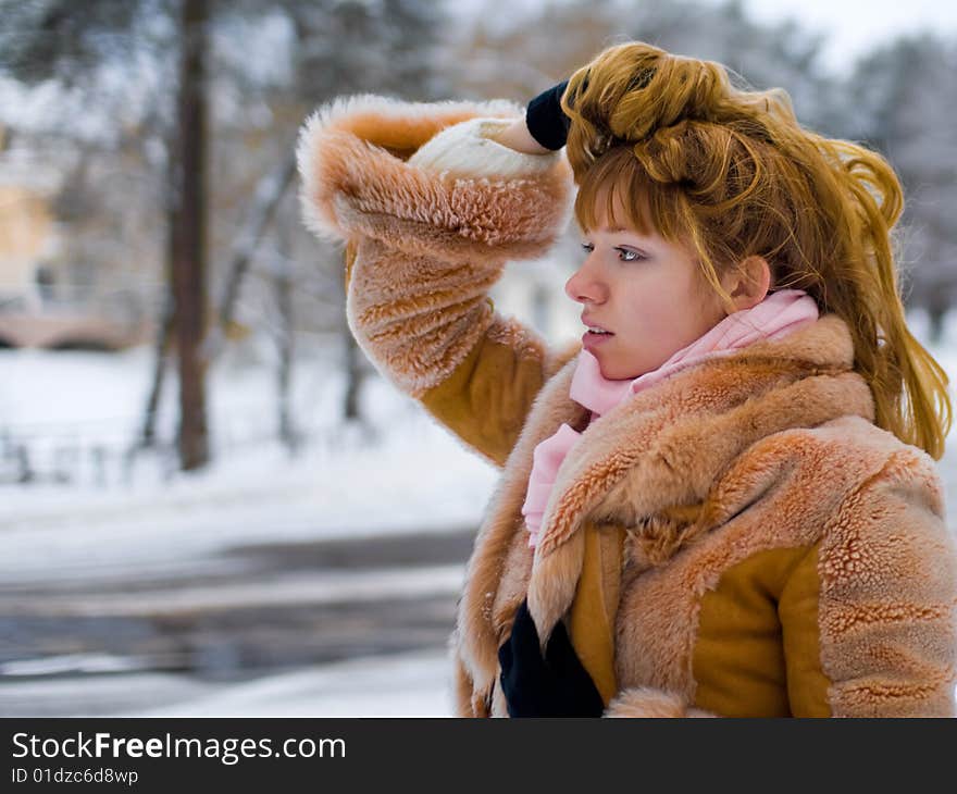 Red-heared girl in short fur coat outdoors - shallow DOF. Red-heared girl in short fur coat outdoors - shallow DOF