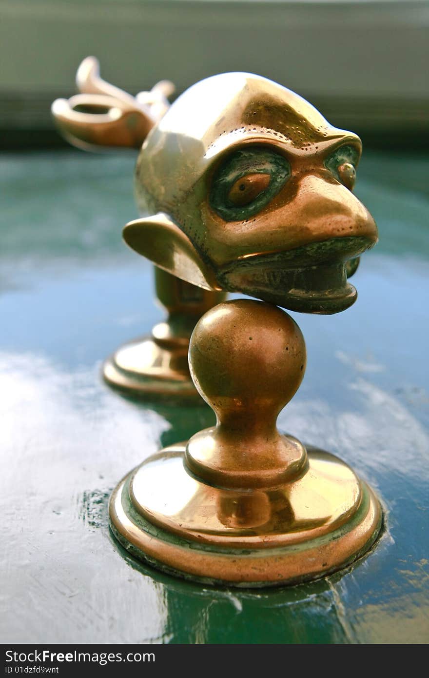 A bronze door knob, in the form of a fish, against a green wooden door. A bronze door knob, in the form of a fish, against a green wooden door