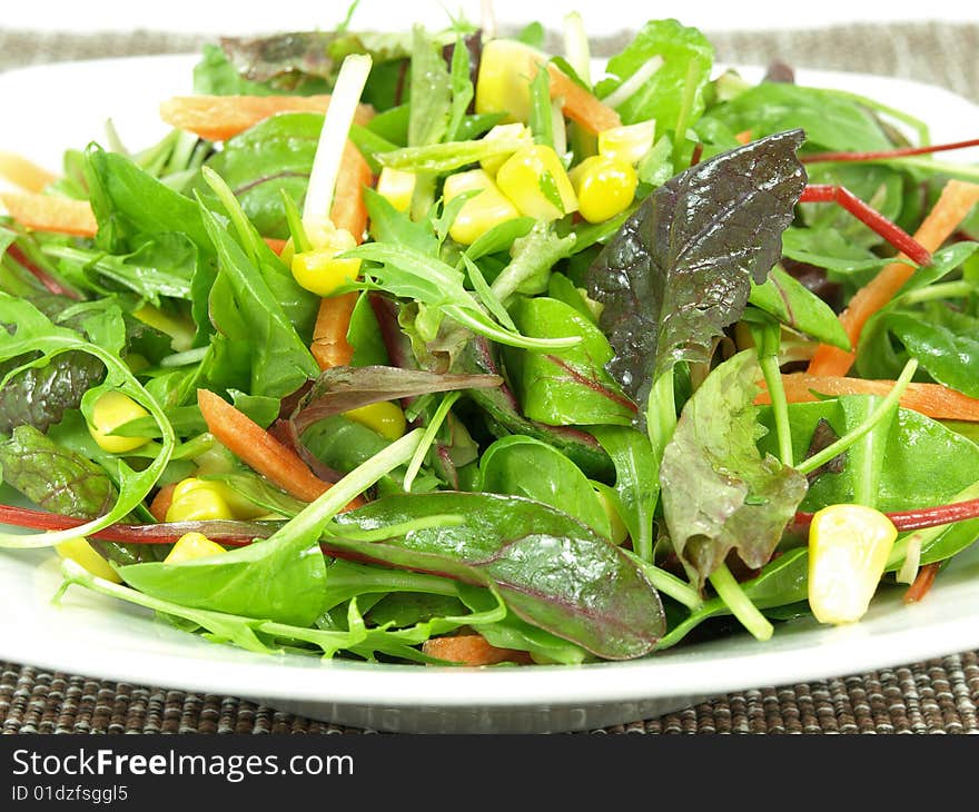 A bowl baby greens, strips of carrots and sweet corn dressed with olive oil and vinegar. A bowl baby greens, strips of carrots and sweet corn dressed with olive oil and vinegar.