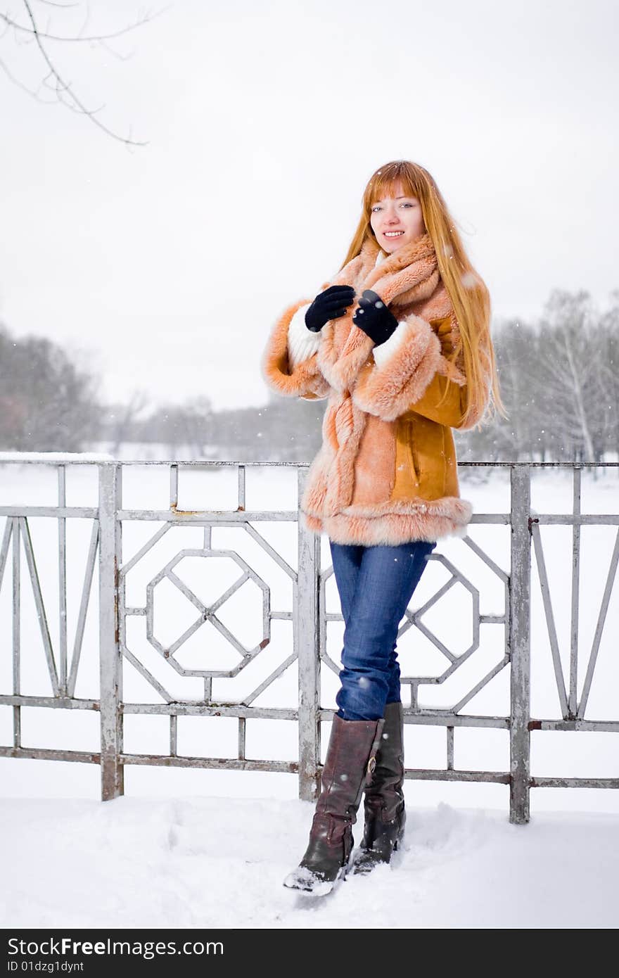 Red-heared girl in short fur coat outdoors - shallow DOF. Red-heared girl in short fur coat outdoors - shallow DOF