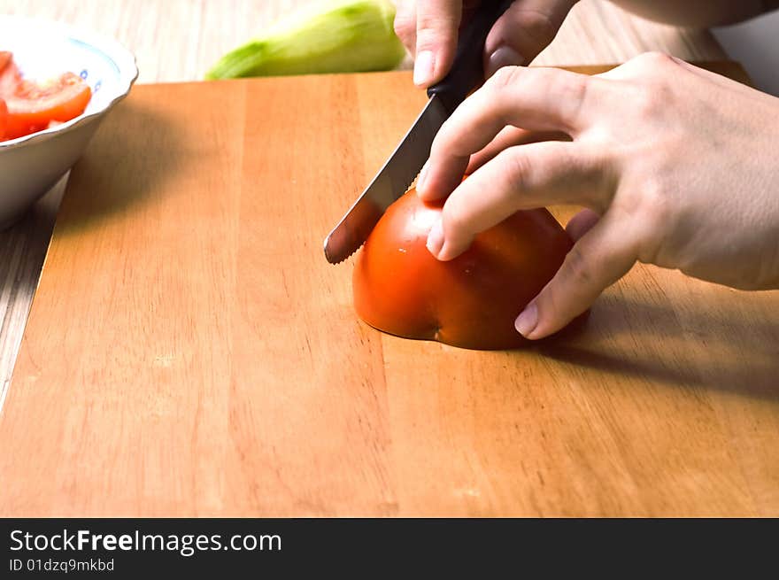 Hands slicing tomatoe on wooden board. Hands slicing tomatoe on wooden board.