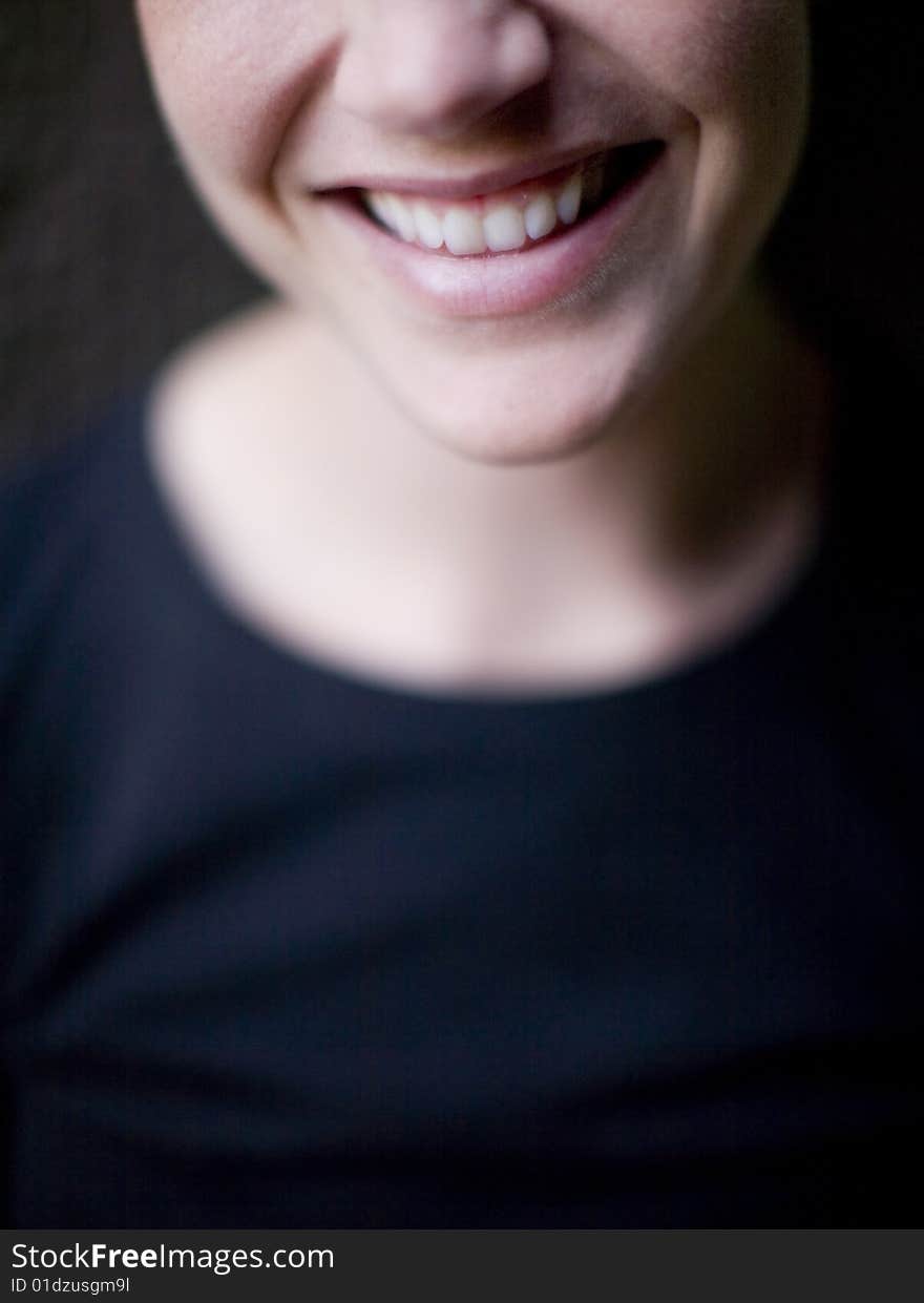 A woman is smiling with a big smile outside in natural light with a black shirt on. A woman is smiling with a big smile outside in natural light with a black shirt on