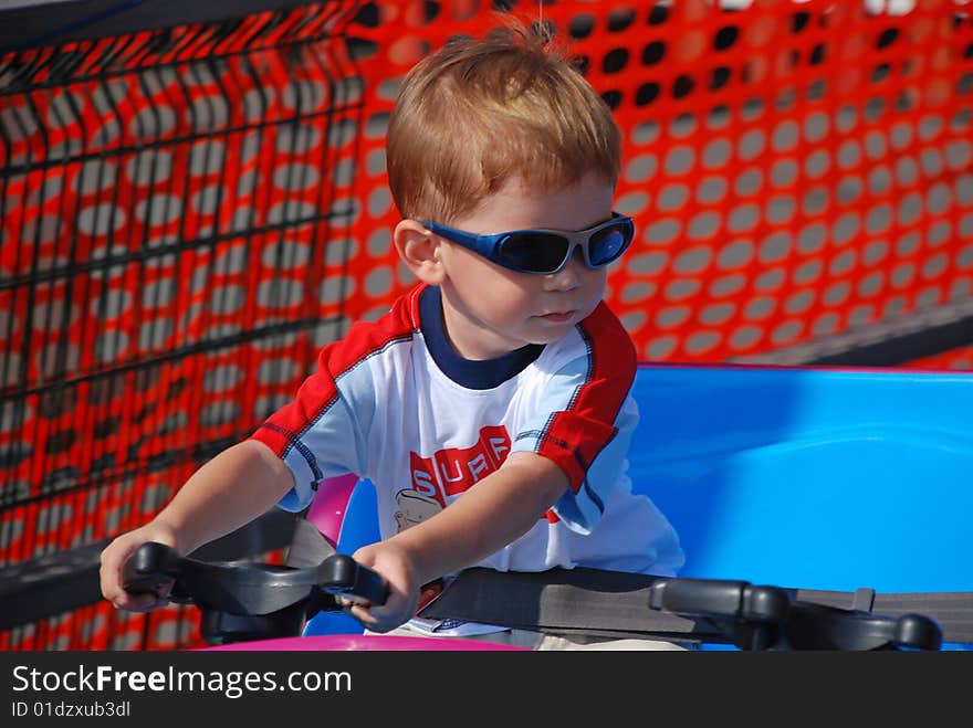 Child with sunglasses on toy car