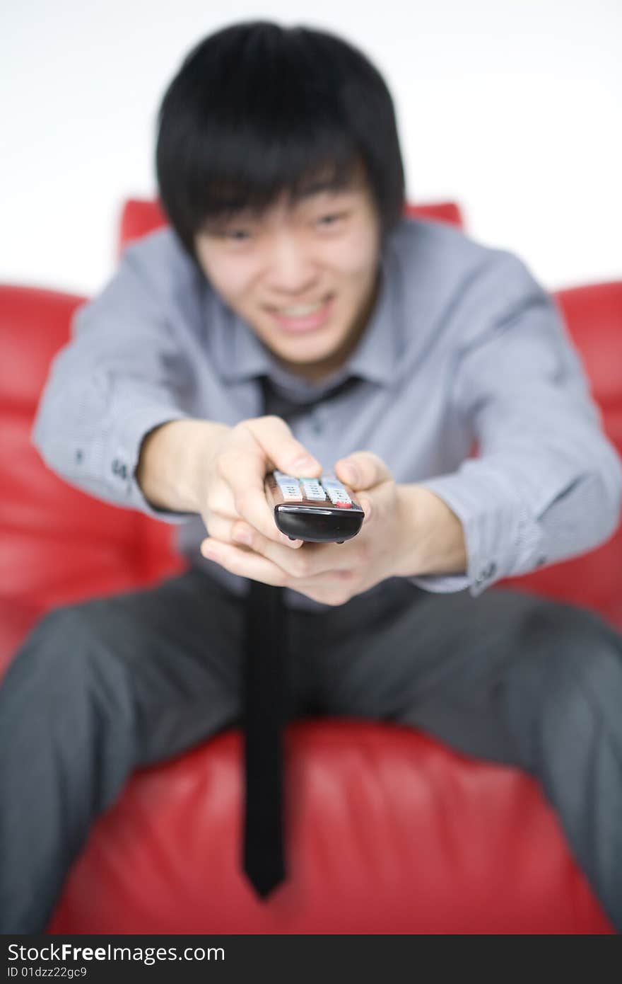 The smiling young man in a grey shirt watches TV