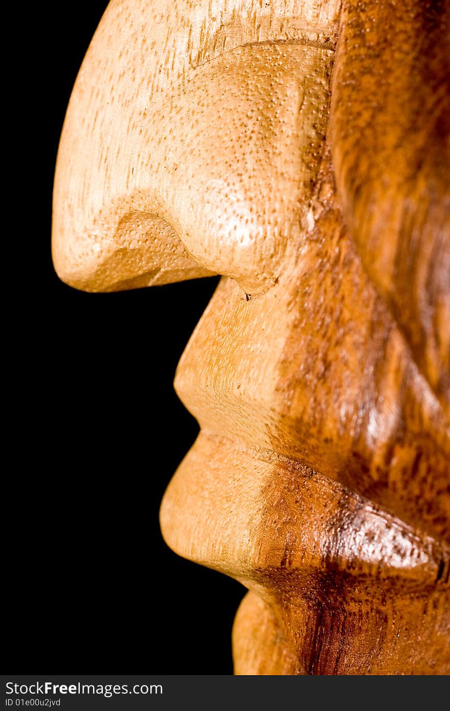Shoot is showing a wooden statue nose and mouth that is hand carved on a black background. Shoot is showing a wooden statue nose and mouth that is hand carved on a black background