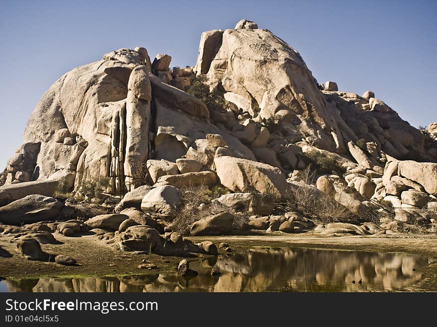 This is a picture of desert water and reflections behind Barker Dam, a natural dam at Joshua Tree National Park.