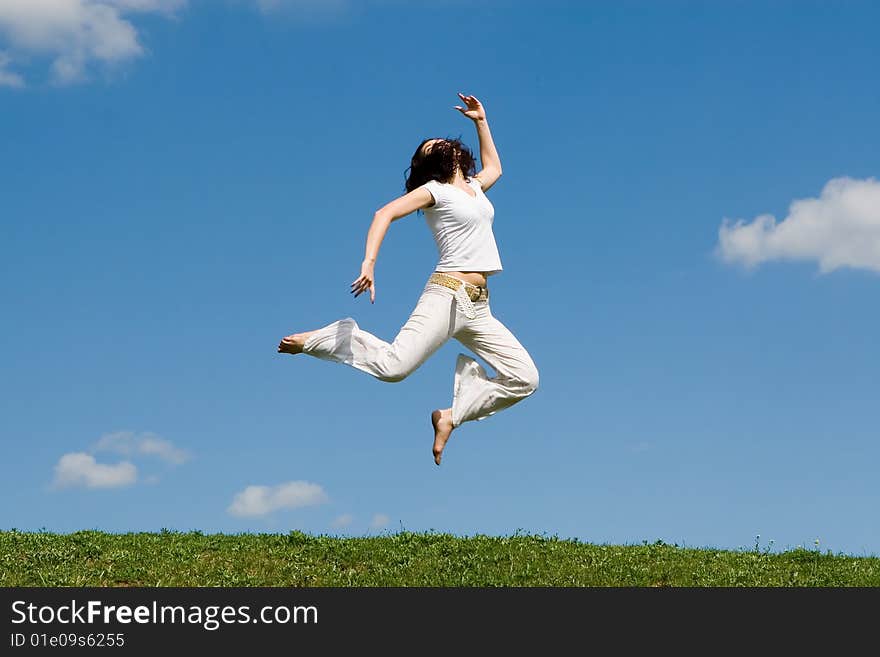 Happy young woman is jumping in green grass