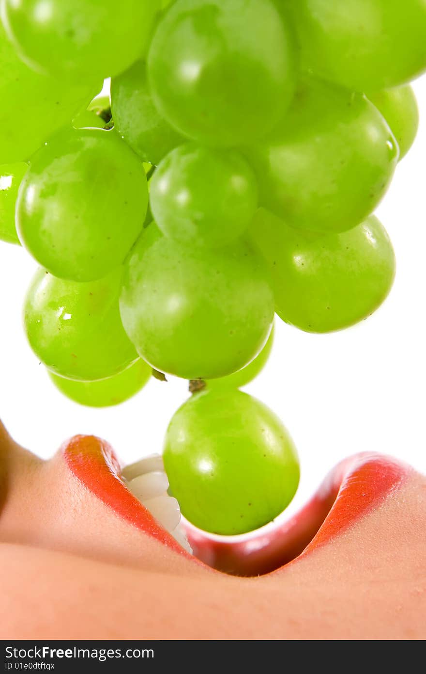 Beautiful young woman eating an grape, isolated in white background