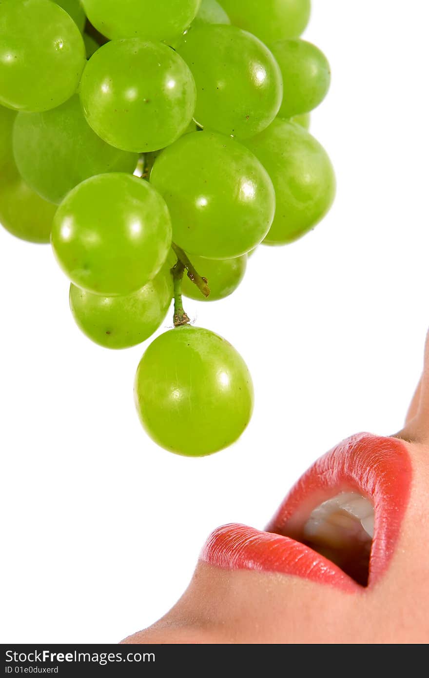 Beautiful young woman eating an grape, isolated in white background