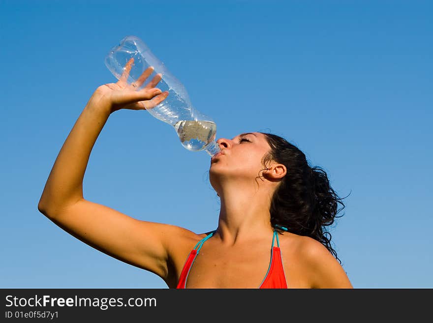 Girl drinking water against blue sky