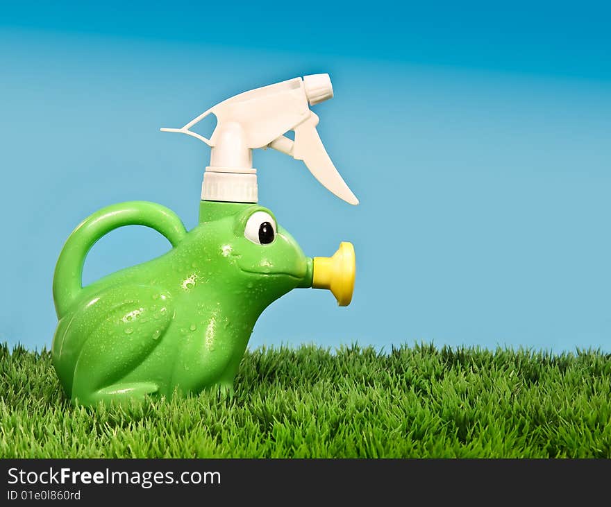 Child's spray bottle on grass with blue background