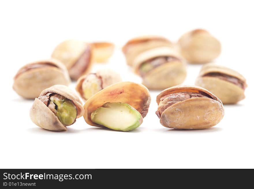 Several pistachios with salt isolated on a white background. Background blurred. Several pistachios with salt isolated on a white background. Background blurred.