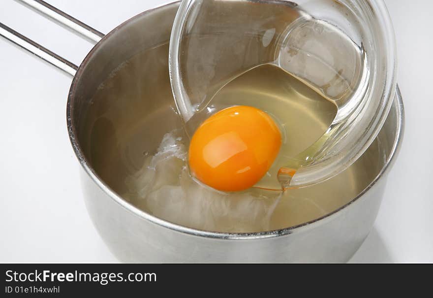 Cracked Egg In Bowl And Water In Pan