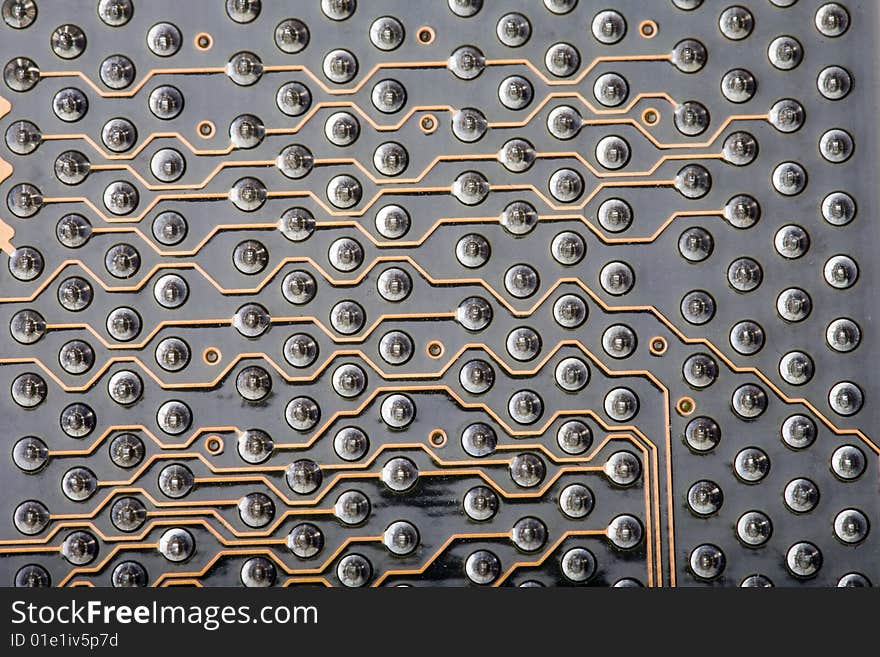 Macro close-up of a detail section of the back of a computer circuit board. This is the area where the PCI slots are located, with rows of soldering points and data pathways along the circuit connections. Macro close-up of a detail section of the back of a computer circuit board. This is the area where the PCI slots are located, with rows of soldering points and data pathways along the circuit connections.