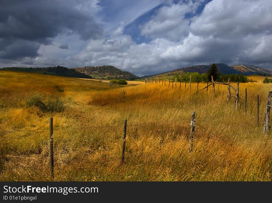 Fall storm on a farm with a fence in the forground