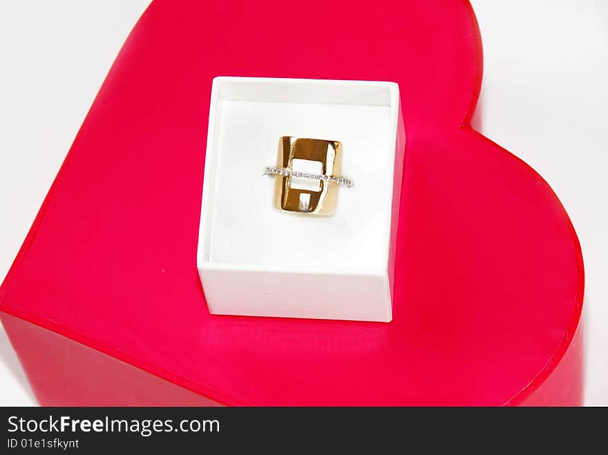 Golden ring gift in white box over red heart background. Golden ring gift in white box over red heart background