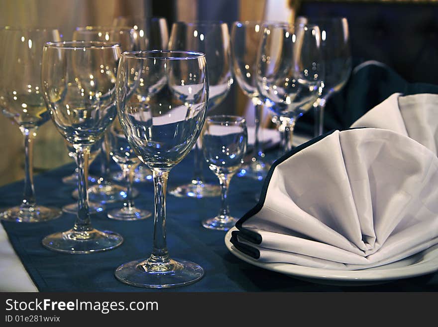 Glass tableware with the blue specks of light alongside the serviette. Glass tableware with the blue specks of light alongside the serviette