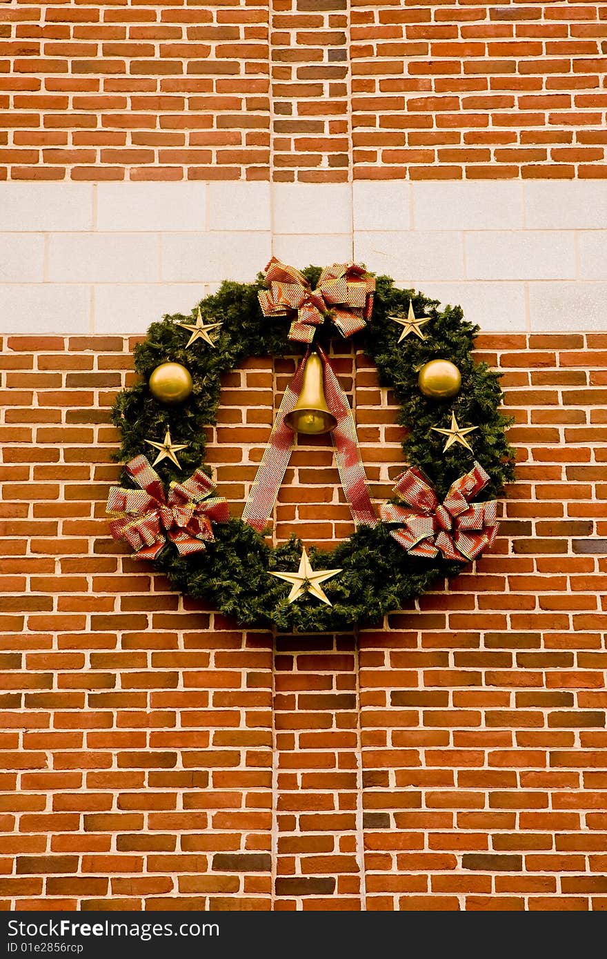 A christmas wreath with gold ornaments on a brick wall. A christmas wreath with gold ornaments on a brick wall