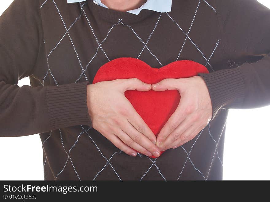 A young man shows a heart shape with his hands on a red heart-shaped pillow. Isolated over white. A young man shows a heart shape with his hands on a red heart-shaped pillow. Isolated over white.