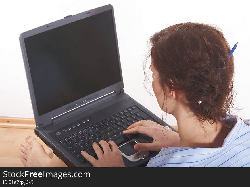 A young woman at home sitting on the floor with her laptop. She has a pencil in her hair. Lots of copyspace on the laptop screen. A young woman at home sitting on the floor with her laptop. She has a pencil in her hair. Lots of copyspace on the laptop screen.