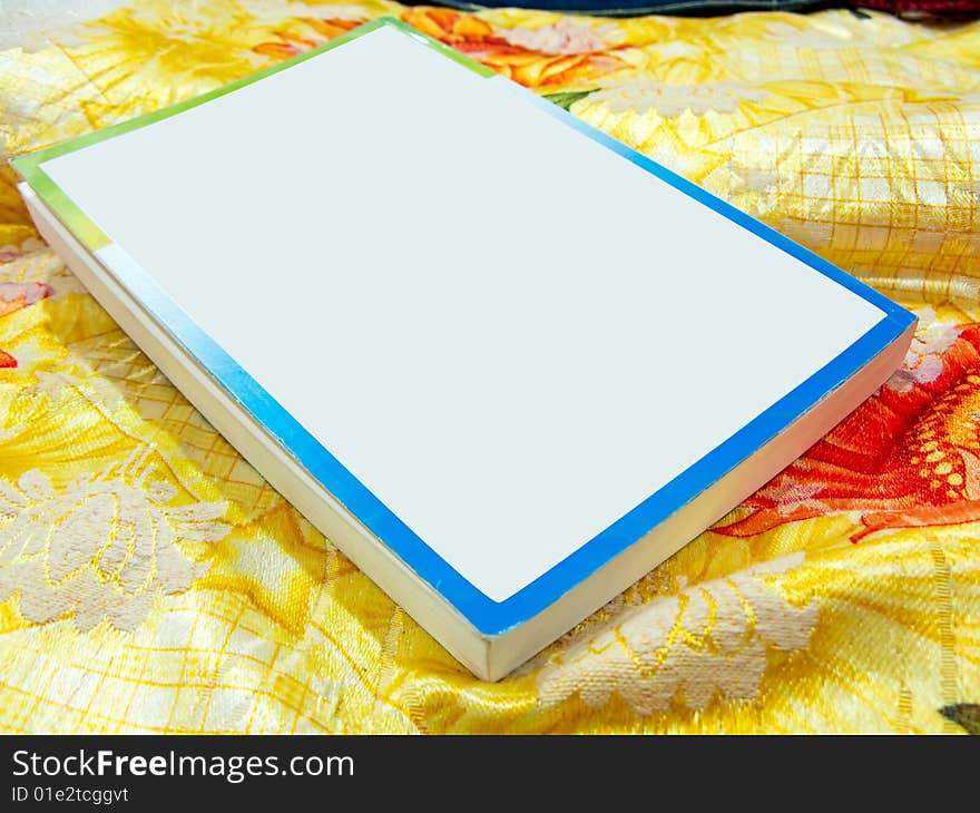 Photo of a book with blank cover on kept on a colorful sheet. Photo of a book with blank cover on kept on a colorful sheet