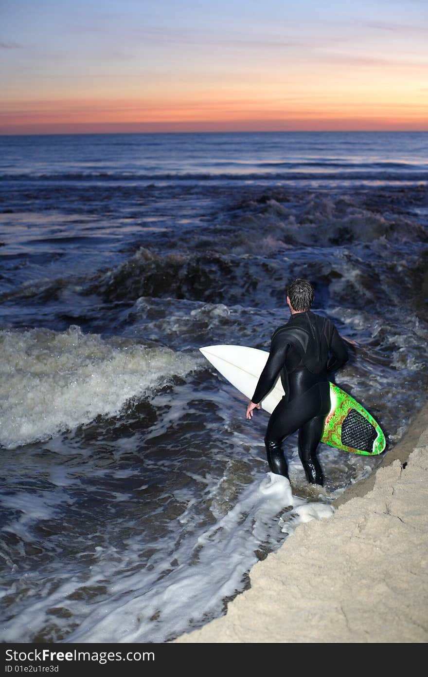 A surfer heads out for a sunset sessions