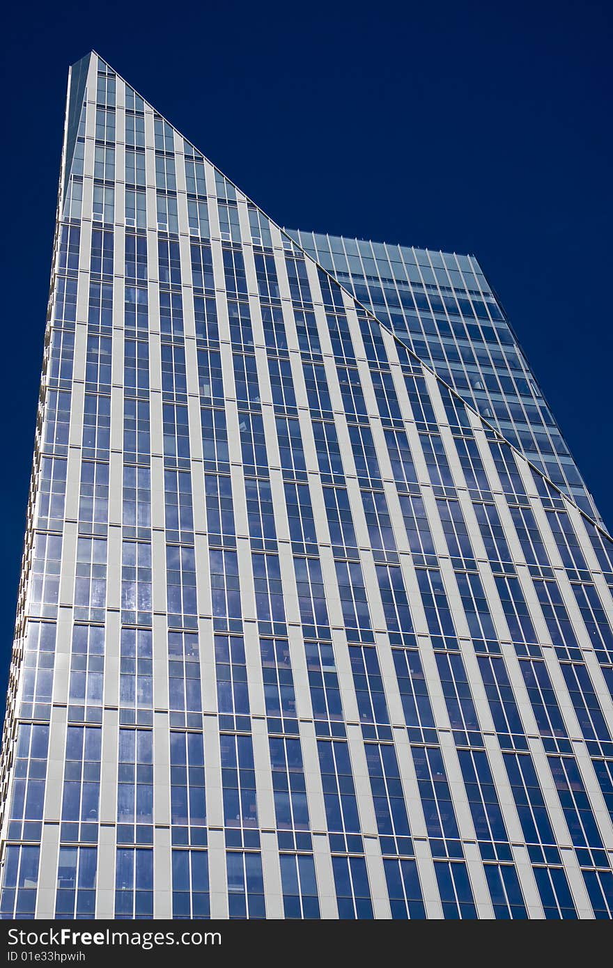 A modern blue glass office tower rising against a blue sky. A modern blue glass office tower rising against a blue sky