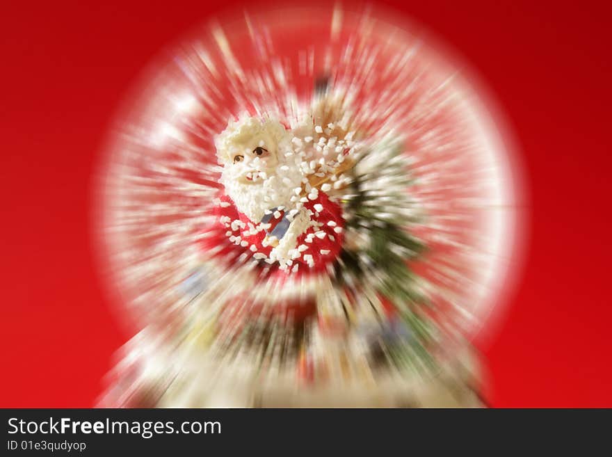 Santa claus figurine on a glass snowing ball, red background studio shot