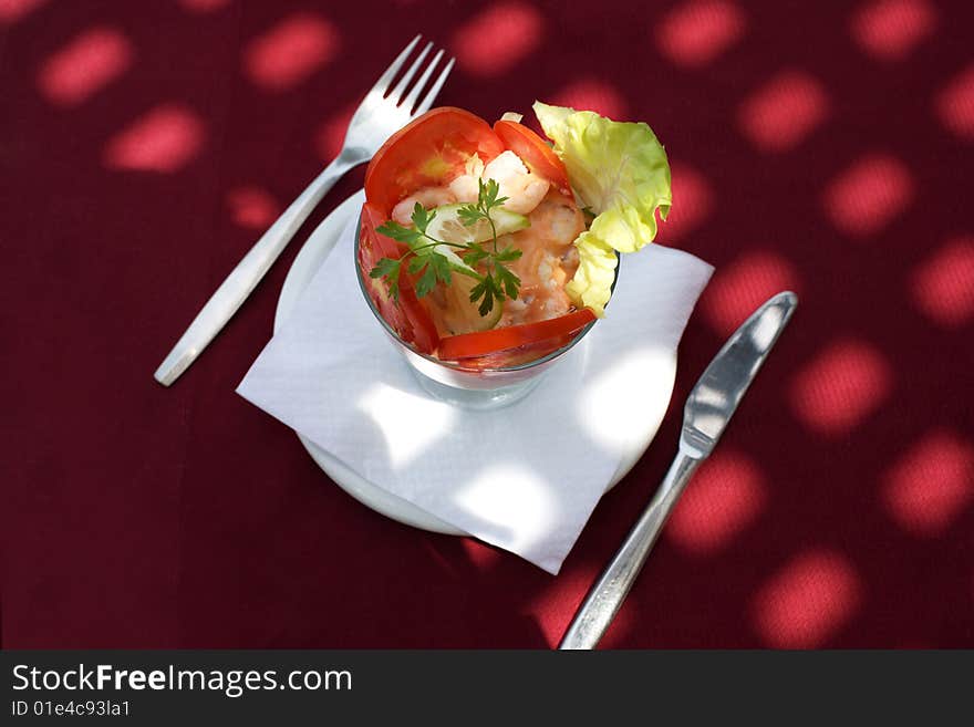 Prawn cocktail at red tablecloth with sunlight spots