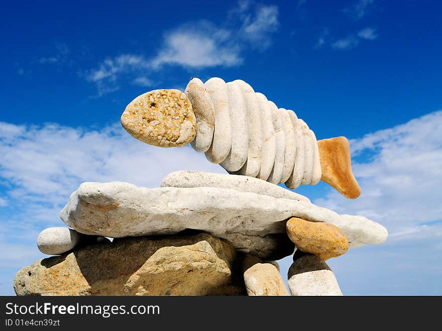 Pile of sea stones in the form of fish and the dark blue sky. Pile of sea stones in the form of fish and the dark blue sky