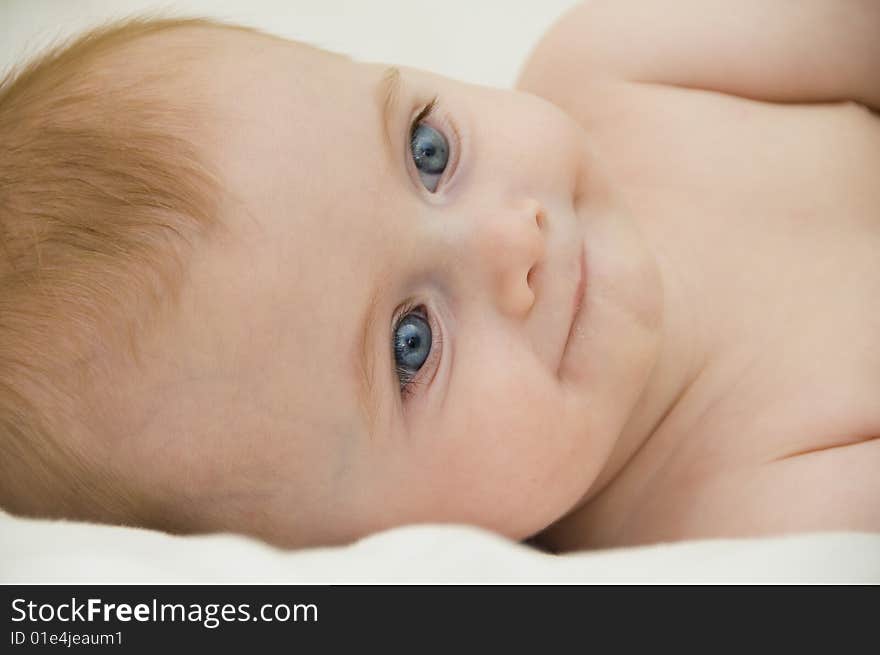 Cute baby girl playing on a bed with a white background