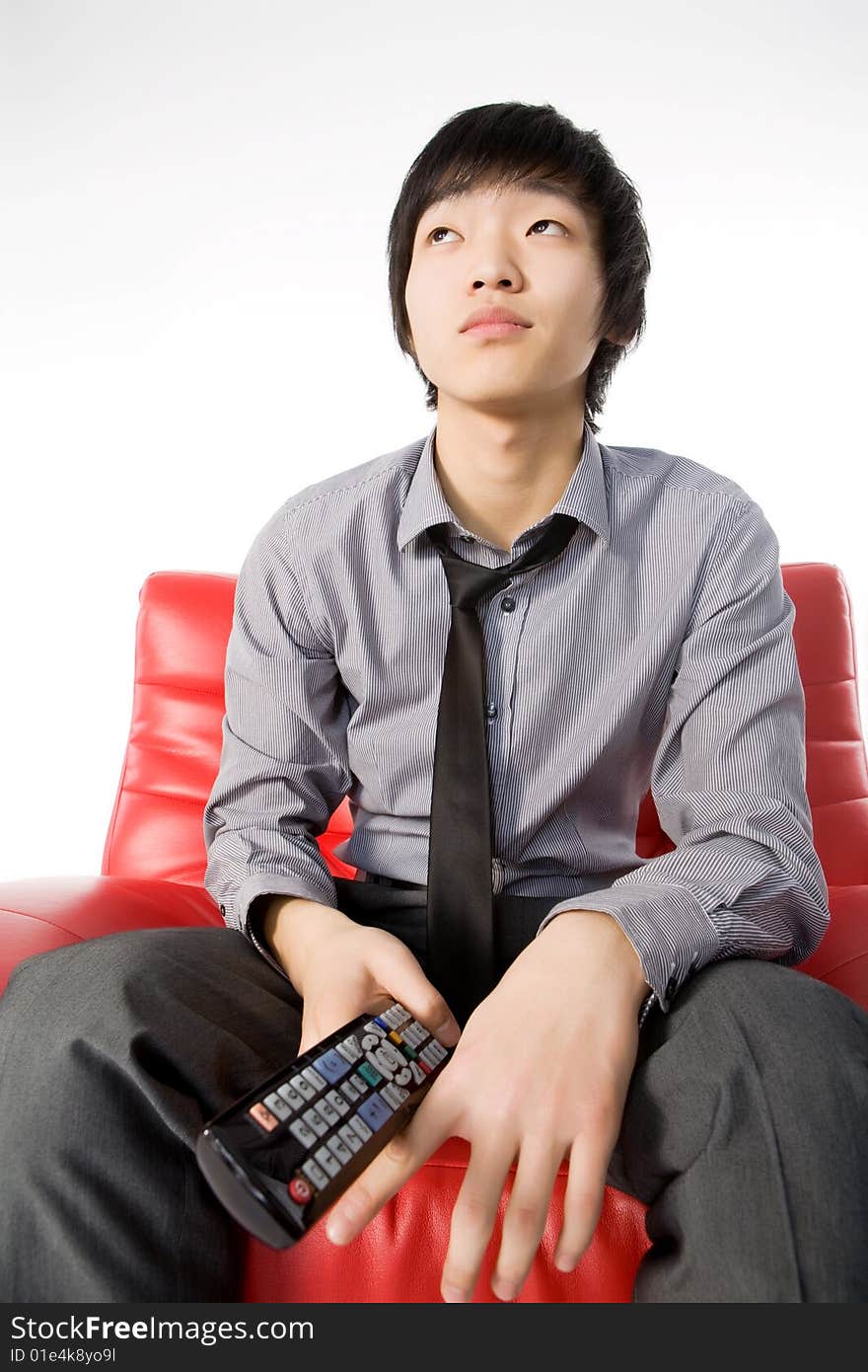 The smiling young man in a grey shirt watches TV