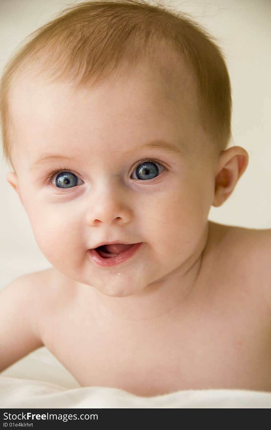 Cute baby girl playing on a bed with a white background