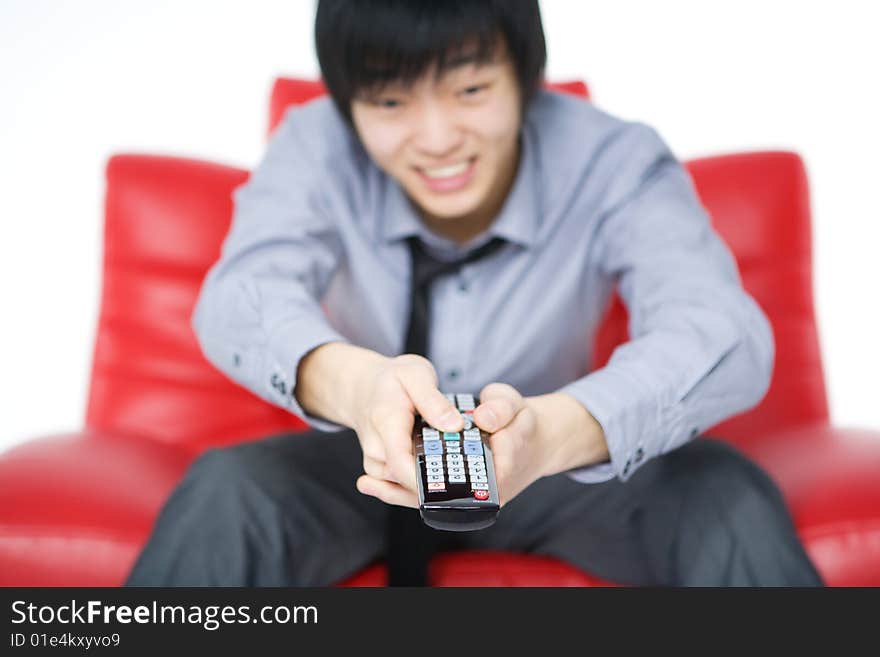 The smiling young man in a grey shirt watches TV