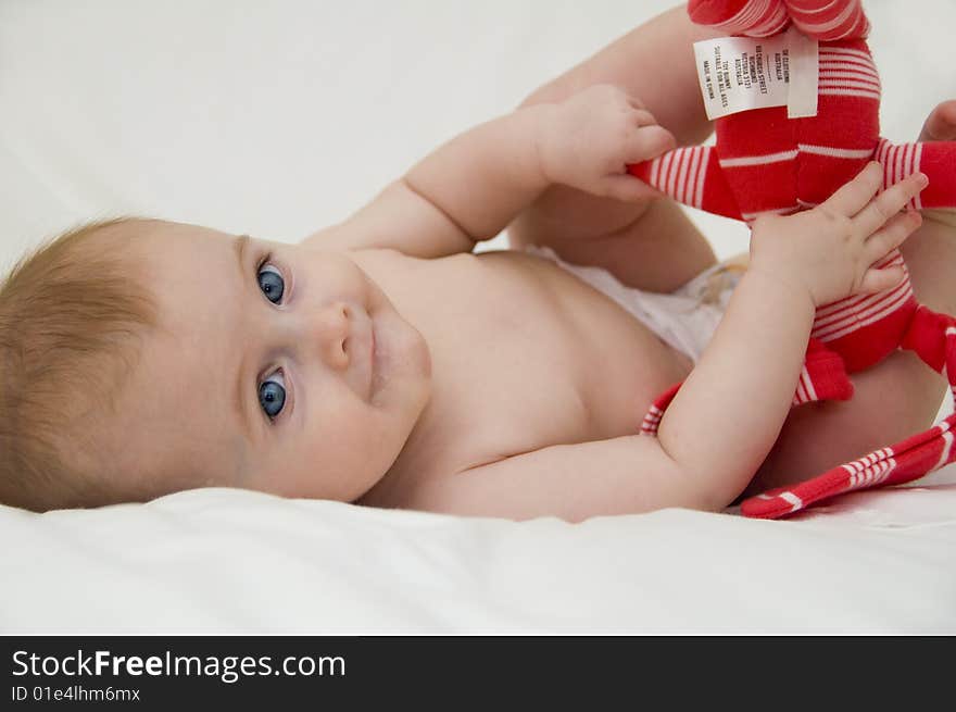 Cute baby girl playing on a bed with a white background