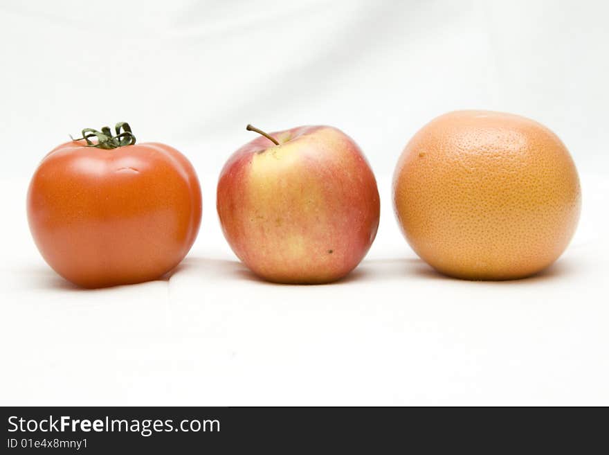 Apple, tomato and orange on the white not isolated background