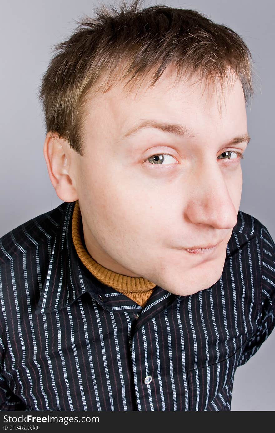 Young man with curiosity looks in grey background. Young man with curiosity looks in grey background