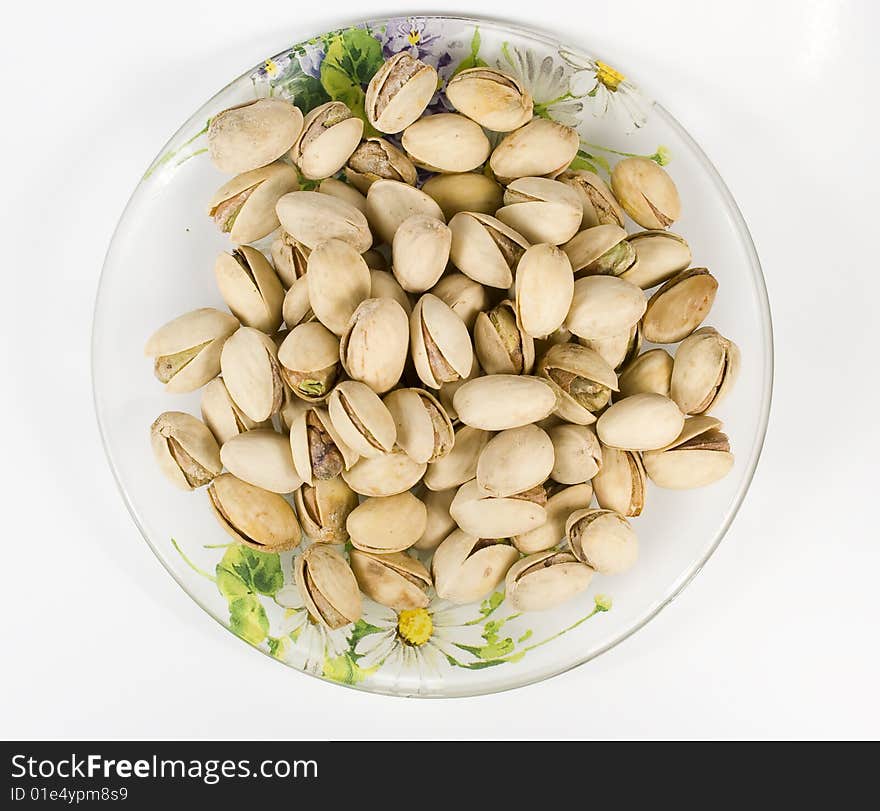 Pistachios on saucer with nutshell on white