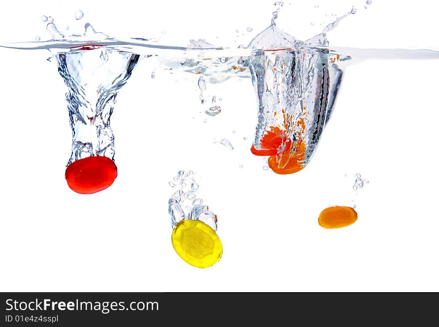 Colored sugarplums falling into the water,white background