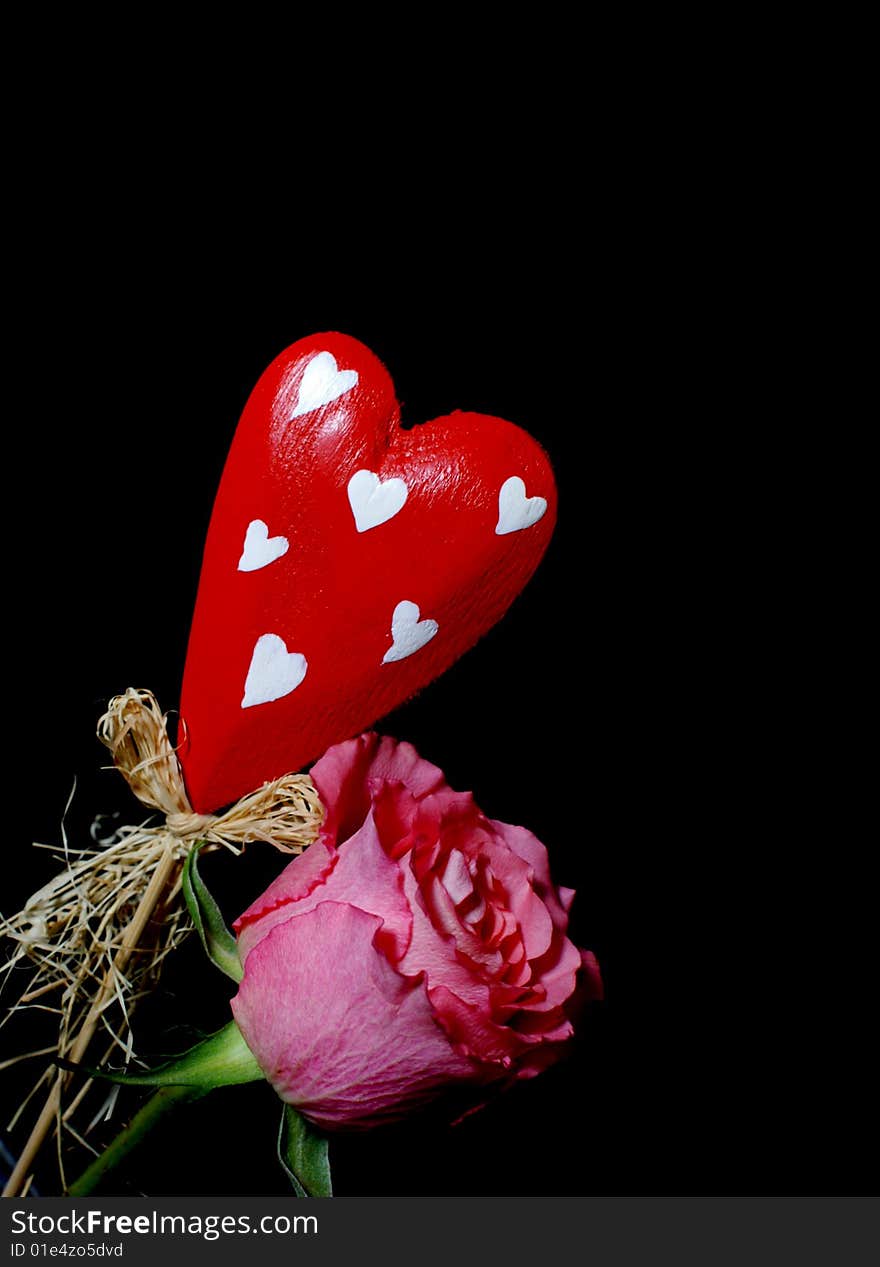 Red wooden heart and a  red rose isolated on black. Red wooden heart and a  red rose isolated on black.