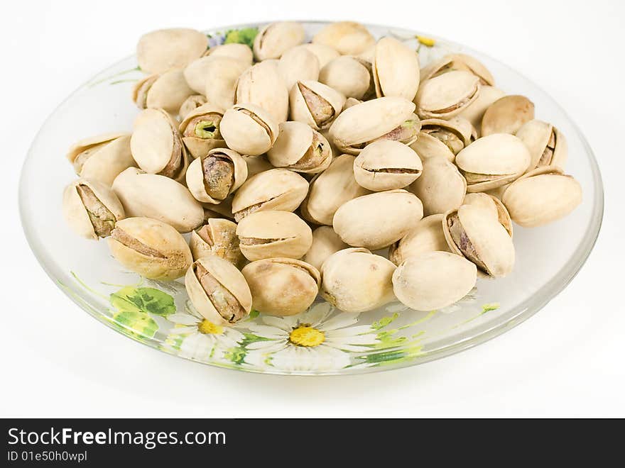 Pistachios on saucer with nutshell on white