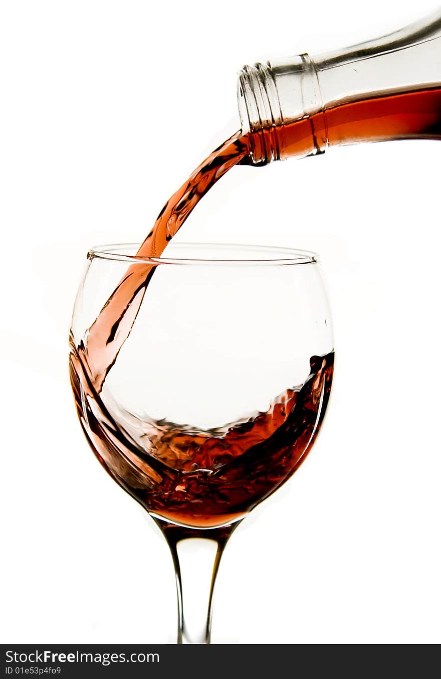 Pouring red wine in glass isolated on white