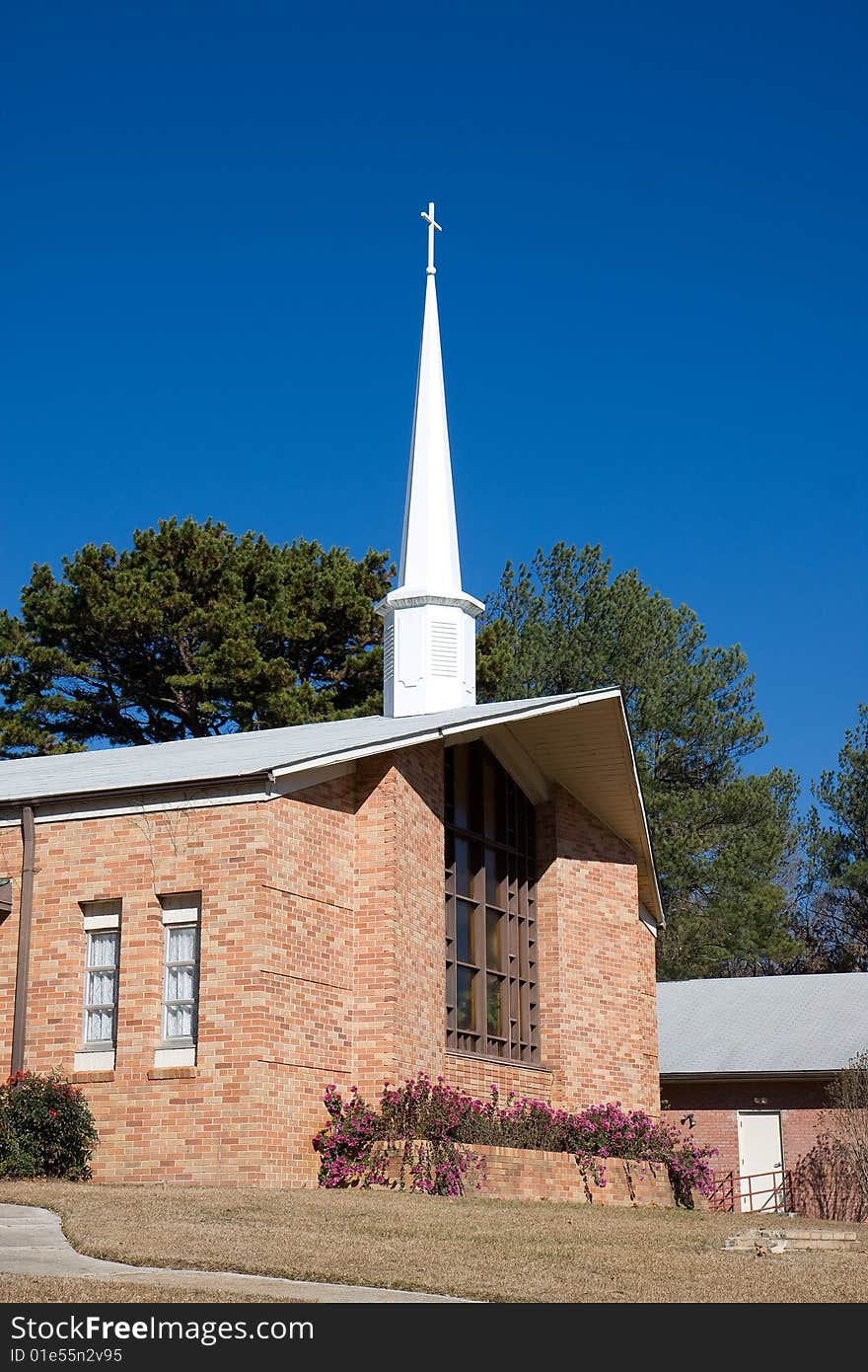 A small brick church and steeple against a blue sky. A small brick church and steeple against a blue sky