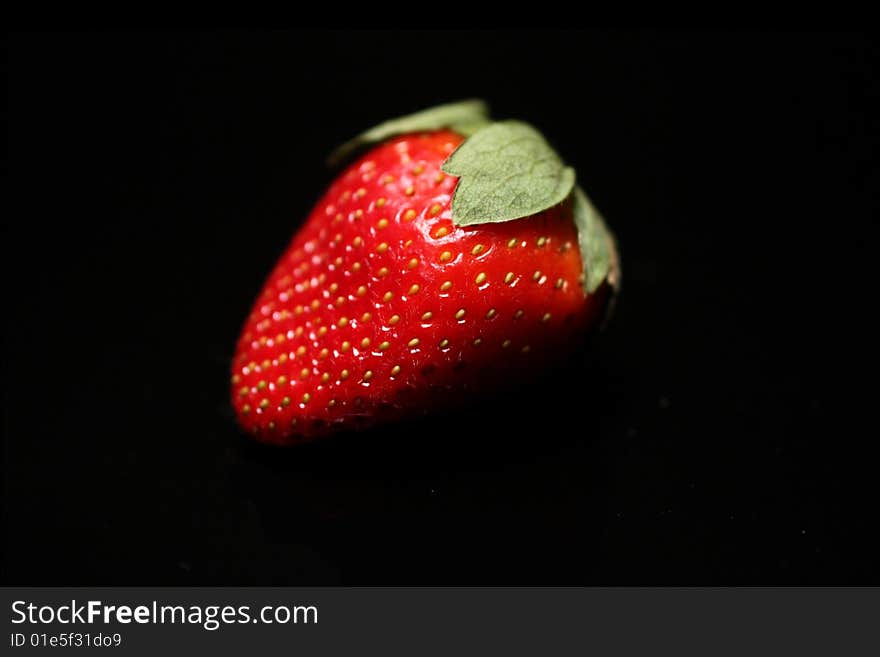 Photo of a strawberry against a black background.