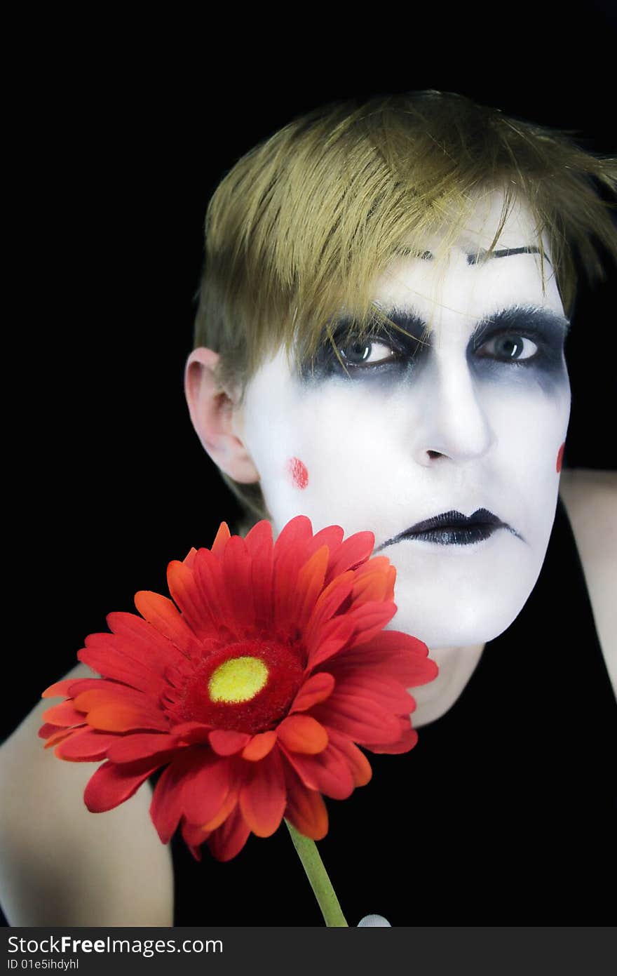 Gloomy mime with a red flower on a black background. Gloomy mime with a red flower on a black background