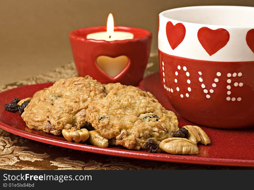 Oatmeal Raisin Cookies on a heart shaped plate with Valentines mug and candle. Oatmeal Raisin Cookies on a heart shaped plate with Valentines mug and candle