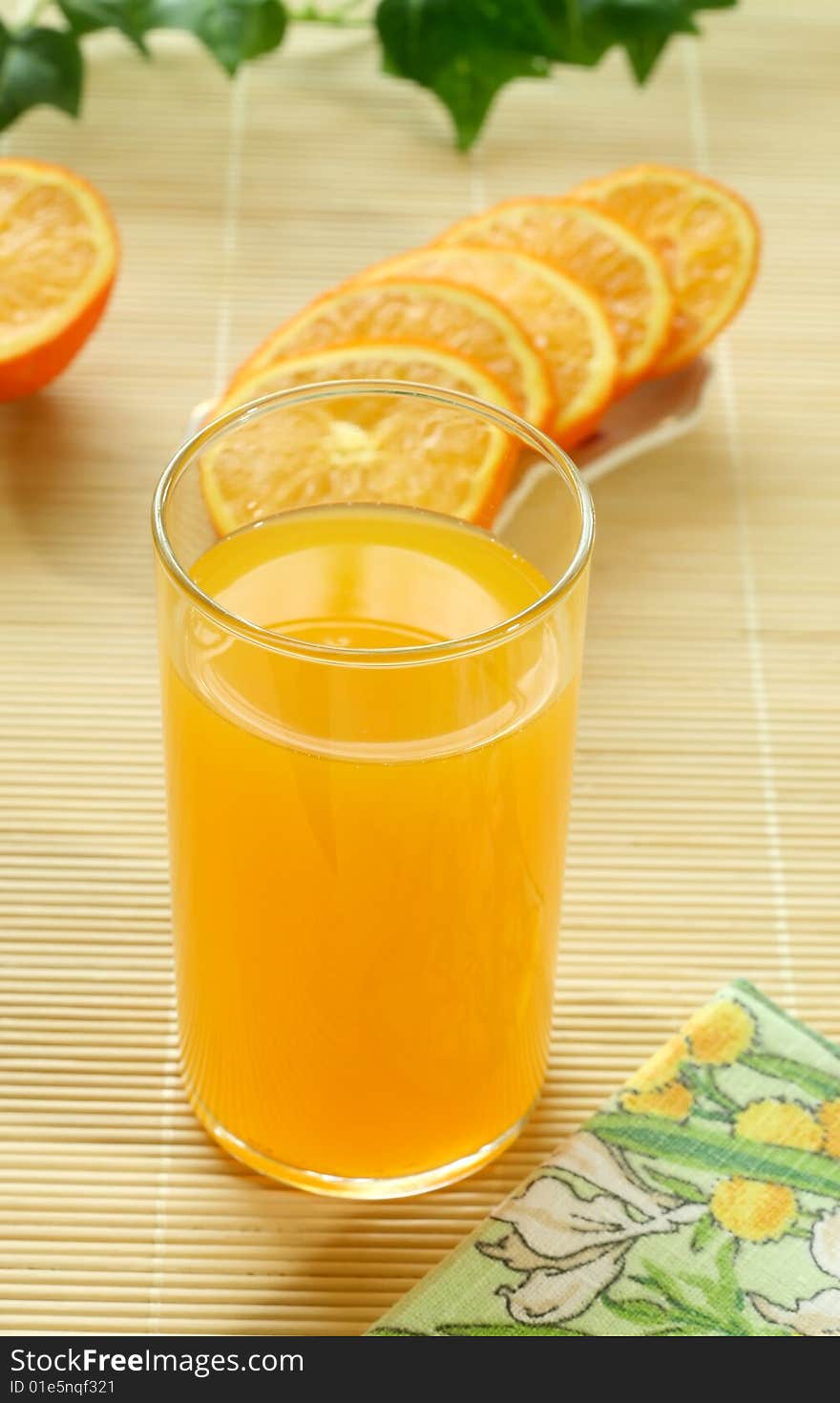 Orange juice in a glass and oranges, closeup