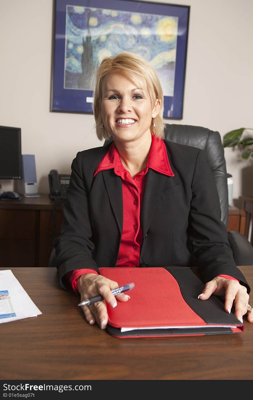 A business woman sitting at her desk with her sales binder in hand. A business woman sitting at her desk with her sales binder in hand